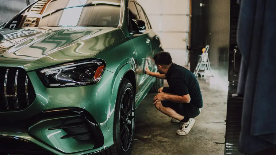 Technician working along the front fender of a green Mercedes-AMG GLE 63